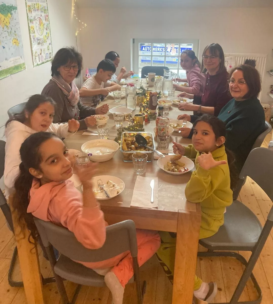 satt & schlau - Bild für den Bildlauf am Ende der Startseite - Es zeigt eine Gruppe von Kindern und Lehrkräften beim Mittagessen.