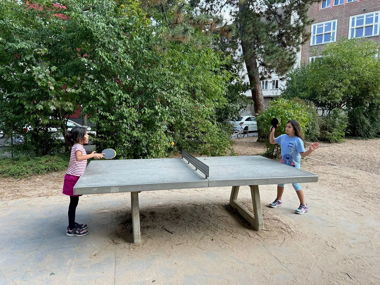 satt & schlau - Bild für den Bildlauf am Ende der Startseite - Es zeigt zwei Kinder beim Tischtennis auf einem Spielplatz.