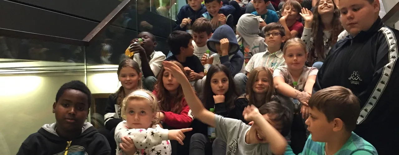 satt & schlau - Bild für die Seite "Kontakt" - Es zeigt eine Gruppe freudiger Kinder auf der Treppe eines Museums.