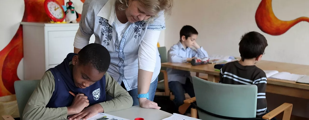 satt & schlau – Projekt satt & schlau - Bild für die Seite "Projekt" - Es Zeigt eine Lehrkraft die Kindern in einer Klasse bei der Projektarbeit hilft.